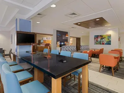 a waiting room with a large table and chairs at Holiday Inn Express Hotel & Suites Ft. Lauderdale-Plantation by IHG in Plantation