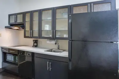 a kitchen with black cabinets and a refrigerator at Candlewood Suites Fort Lauderdale Airport-Cruise by IHG in Fort Lauderdale