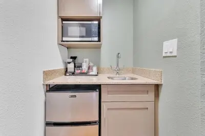 a small kitchen with a sink and a microwave at Rodeway Inn & Suites Fort Lauderdale Airport & Cruise Port in Fort Lauderdale