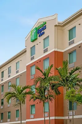 a hotel with palm trees in front of it at Holiday Inn Express & Suites Pembroke Pines-Sheridan St by IHG in Pembroke Pines