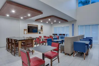 a dining room with tables and chairs and a tv at Holiday Inn Express Hotel & Suites Fort Lauderdale Airport/Cruise Port by IHG in Fort Lauderdale