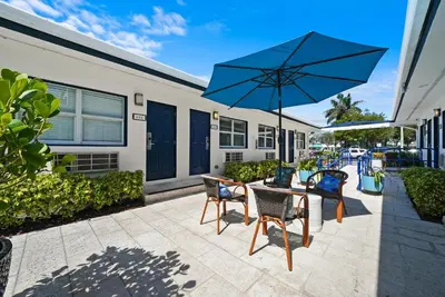 a patio with a table and chairs and an umbrella at Hollywood Beach Suites and Hotel in Hollywood