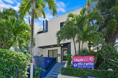 a white house with palm trees in front of it at Hollywood Beach Suites and Hotel in Hollywood