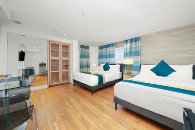 a hotel room with two beds and a desk at Hollywood Beach Suites and Hotel in Hollywood