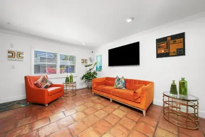 a living room with two orange chairs and a flat screen tv at Hollywood Beach Suites and Hotel in Hollywood