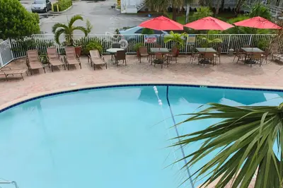 an empty swimming pool with tables and chairs and umbrellas at Collins Hotel in Miami Beach