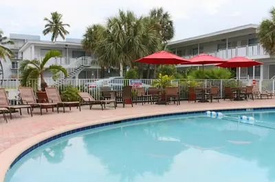 a swimming pool with tables and chairs and umbrellas at Collins Hotel in Miami Beach