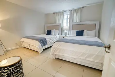 two beds in a white room with a window at Hollywood apartment by the sea in Hollywood