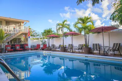 a pool at a hotel with chairs and umbrellas at The Big Coconut Guesthouse - Gay Men's Resort in Fort Lauderdale