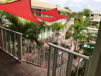 a balcony with a red umbrella and some palm trees at The Big Coconut Guesthouse - Gay Men's Resort in Fort Lauderdale