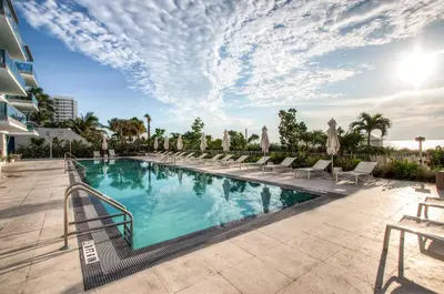 a swimming pool with chaise lounge chairs next to a building at Global Luxury Suites at Monte Carlo in Miami Beach