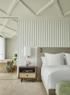 a bedroom with a white bed and a desk at Four Seasons Hotel at The Surf Club in Miami Beach