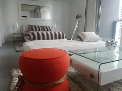 a living room with a red chair and a glass table at Downtown Miami Deluxe Apartment in Miami