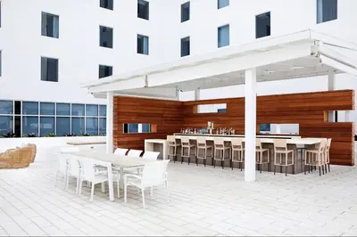 a patio with tables and a bar in a building at AC Hotel by Marriott Miami Aventura in Aventura