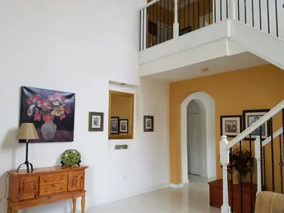 a living room with a staircase and a painting on the wall at My Florida Lake House in Homestead
