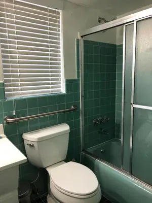 a green tiled bathroom with a toilet and a shower at May-Dee Suites in Florida in Hollywood