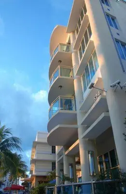 a tall white building with palm trees in front of it at The Fritz Hotel in Miami Beach
