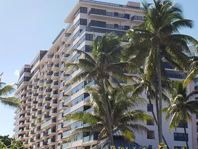 a tall building with palm trees in front of it at 2 Bedroom 2 Bath Beachfront Condo on Miami Beach Millionaire Row in Miami Beach
