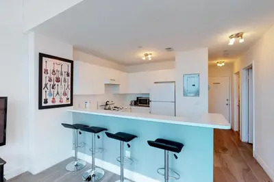a kitchen with a blue counter and stools at Castle Beach: Rumba Suite in Miami Beach