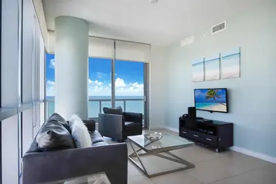 a living room with a couch and a tv at Bluebird Suites Monte Carlo Miami Beach in Miami Beach