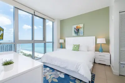 a bedroom with a white bed and a large window at Bluebird Suites Monte Carlo Miami Beach in Miami Beach