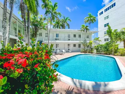 a swimming pool in front of a building with flowers at Winterset in Fort Lauderdale