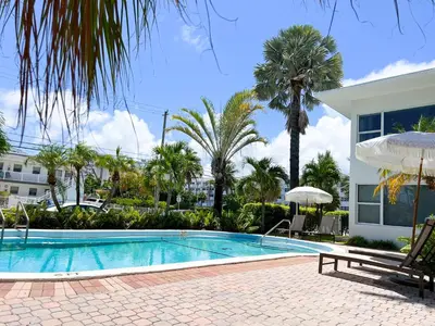 a swimming pool with palm trees and a house at Winterset in Fort Lauderdale