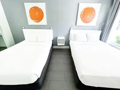 two beds in a room with white sheets at Winterset in Fort Lauderdale
