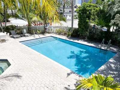 a large blue swimming pool with trees and palm trees at Winterset in Fort Lauderdale