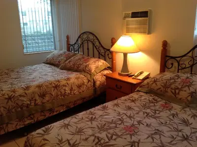 a bedroom with two beds and a lamp on a night stand at Summerland Suites in Fort Lauderdale