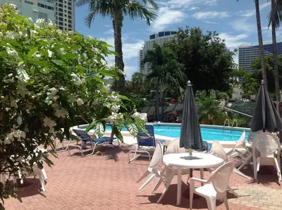 a group of chairs and tables with umbrellas next to a pool at Birch Patio Motel in Fort Lauderdale