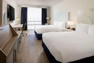 a hotel room with two beds and a television at Hotel Dello Ft Lauderdale Airport, Tapestry Collection by Hilton in Dania Beach