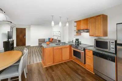 a kitchen with wooden cabinets and a table and a dining room at Hyatt House Fort Lauderdale Airport/Cruise Port in Dania Beach