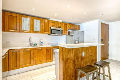 a kitchen with wooden cabinets and stainless steel appliances at Modern Ocean Drive Condo in the Heart of Sobe! in Miami Beach