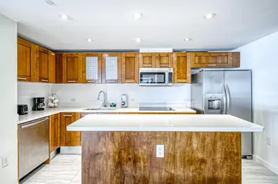 a kitchen with wooden cabinets and stainless steel appliances at Modern Ocean Drive Condo in the Heart of Sobe! in Miami Beach