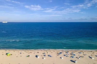 a beach with chairs and umbrellas and the ocean at Modern Ocean Drive Condo in the Heart of Sobe! in Miami Beach