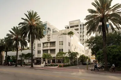 a large white building with palm trees in front of it at Iberostar Waves Berkeley Shore in Miami Beach