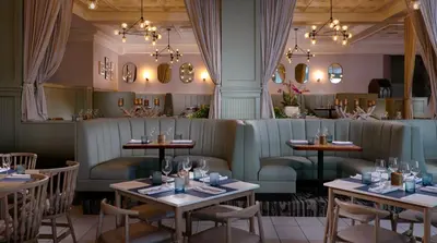 a restaurant with tables and chairs and chandeliers at Pelican Grand Beach Resort, a Noble House Resort in Fort Lauderdale