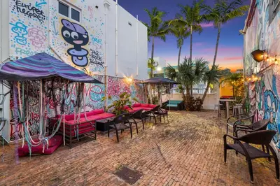 a patio with tables and chairs and a wall with graffiti at The New Yorker Hotel Miami in Miami