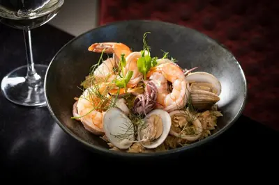 a bowl of shrimp and mushrooms with a glass of wine at Kimpton EPIC Hotel by IHG in Miami