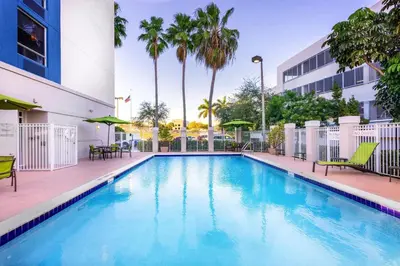 a pool at a hotel with chairs and palm trees at SpringHill Suites by Marriott Miami Airport South Blue Lagoon Area in Miami