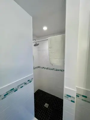 a bathroom with a shower with blue and white tiles at Nobleton Hotel in Fort Lauderdale