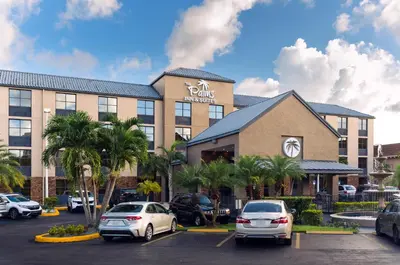 a hotel with cars parked in a parking lot at The Palms Inn & Suites Miami, Kendall, FL in Kendall