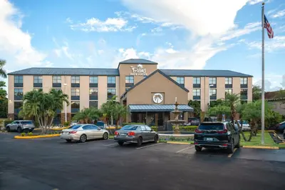 a hotel with cars parked in a parking lot at The Palms Inn & Suites Miami, Kendall, FL in Kendall