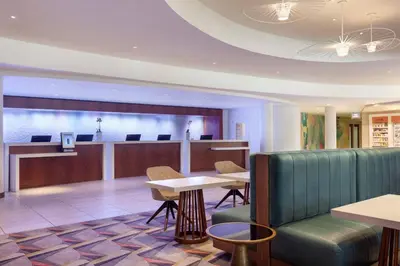a lobby with a waiting area and tables and chairs at Miami Airport Marriott in Miami