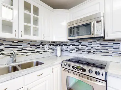 a white kitchen with a sink and a microwave at The Grand Resort and Spa & Worthington All Male in Fort Lauderdale