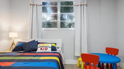 a bedroom with a bed and two chairs and a window at Family getaway in Sunny Isles - 2nd floor in Miami Beach