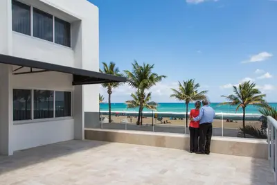 a couple standing on the balcony of a house looking at the beach at Premiere Hotel in Fort Lauderdale