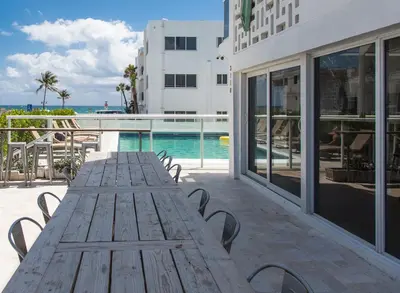 a wooden table on a patio next to a swimming pool at Premiere Hotel in Fort Lauderdale