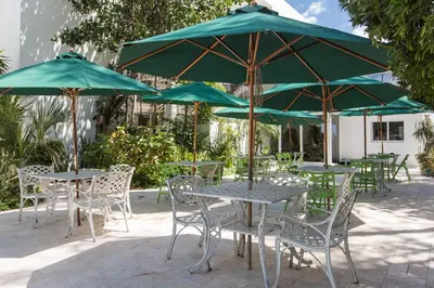 a group of tables and chairs with green umbrellas at Premiere Hotel in Fort Lauderdale